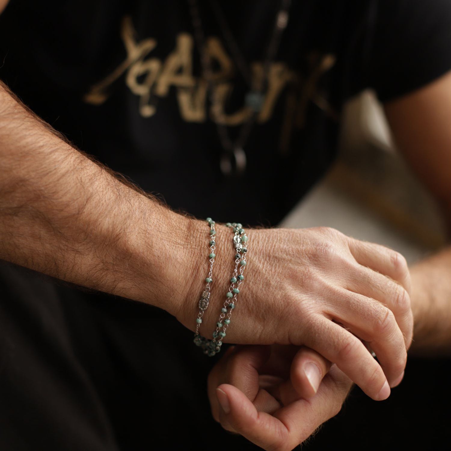 Yoga Teacher Valentin trägt eine Halskette aus Sterling Silber mit Buddha-Emblemen und Jadeperlen und Buddhaamuletten als Armband