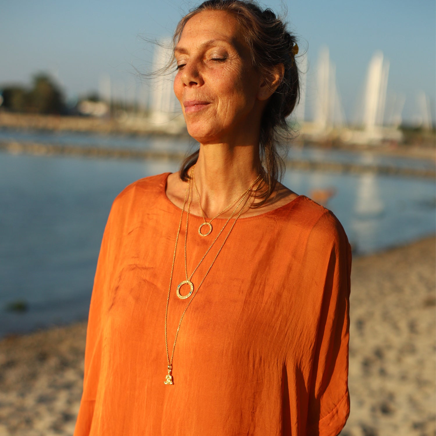 Die Berliner Unternehmerin Cora Schwind kombiniert einen Lehrender-Buddha-Schmuckanhänger aus vergoldetem Sterling Silber  mit anderem Symbol Schmuck von ETERNAL BLISS