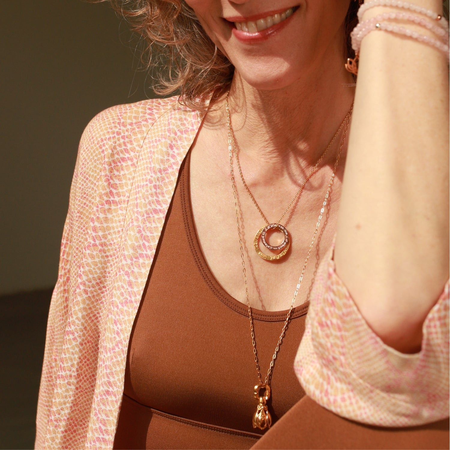 Elena Lustig, Yoga-Lehrerin in Berlin, kombiniert einen vergoldeten Lotus-Glöckchen-Anhänger von ETERNAL BLISS mit Mantra Schmuck