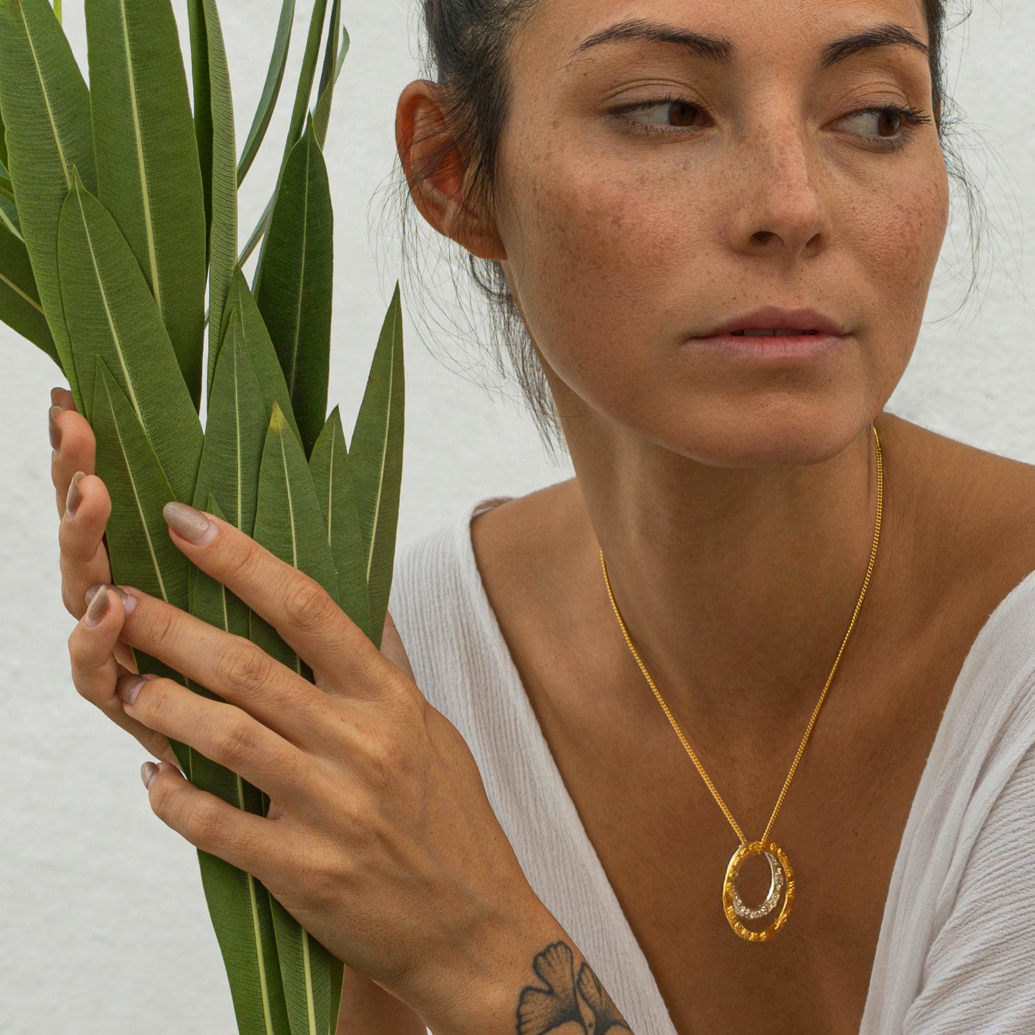 Yoga Teacher Steffi trägt den Kali Mantra Anhänger aus vergoldetem Sterling Silber von Eternal Bliss aus der Yoga Schmuckkollektion. Bild mit Blumen.