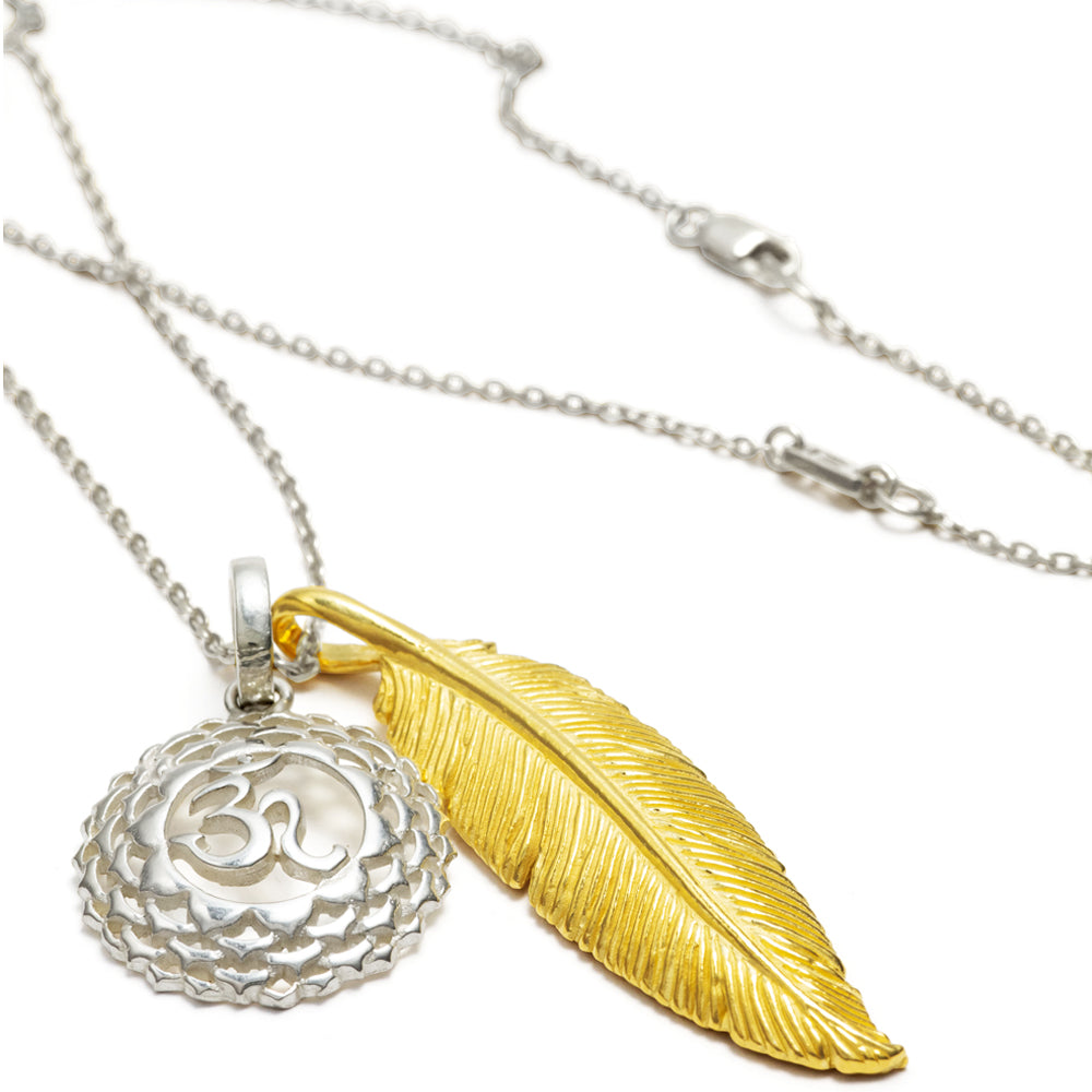 Hochwertige Halskette bicolor "Leichtigkeit & Weite" zusammengestellt aus einem silbernen Kronenchakraanhänger, einem vergoldeten Federanhänger und einer feinen Ankerkette, liegende Ansicht